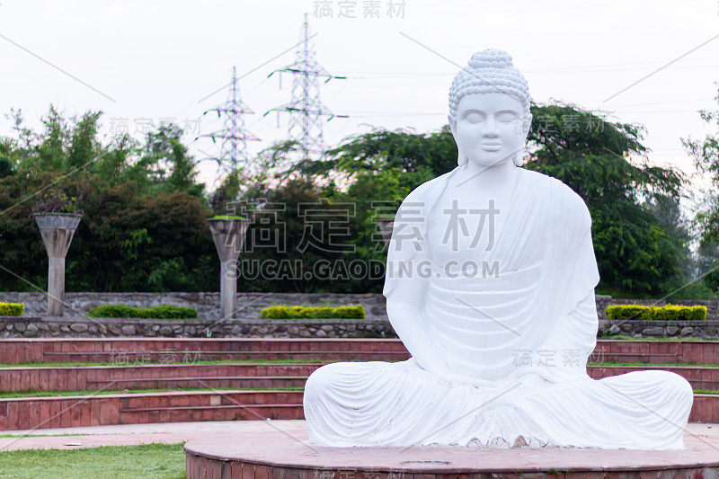 正面拍摄的白色佛像在和平的姿态与电网塔在背景