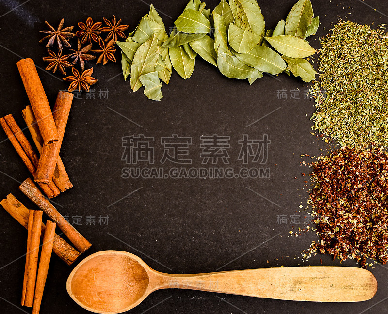 厨房中的药草，香料框架，肉桂棒，八角，木勺，石黑桌上的各种香料