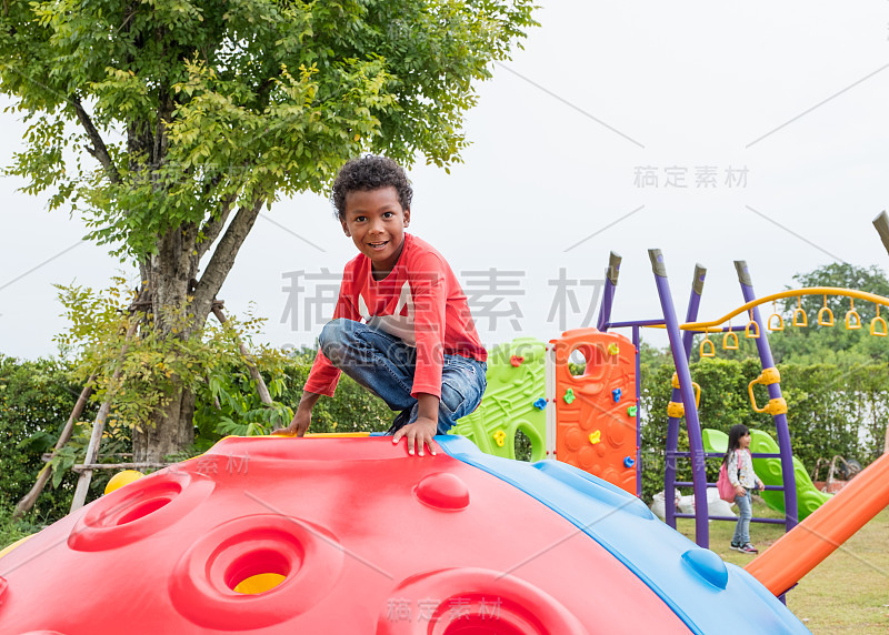 美国黑人小男孩在学校操场上玩着好玩的攀爬玩具，回到学校进行户外活动