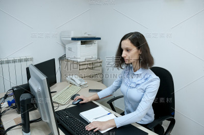 黑发女孩在办公室的电脑前工作