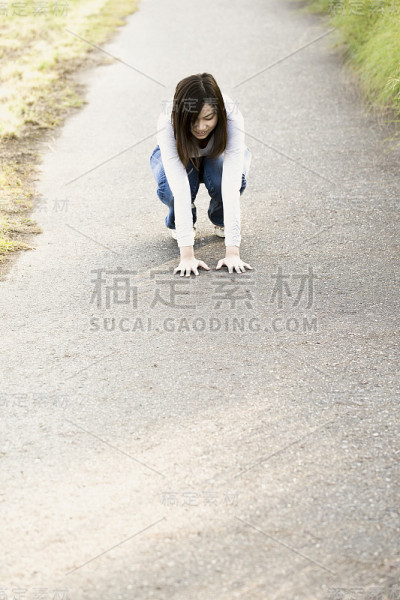 一个年轻的日本女人蹲在郊区的道路上。