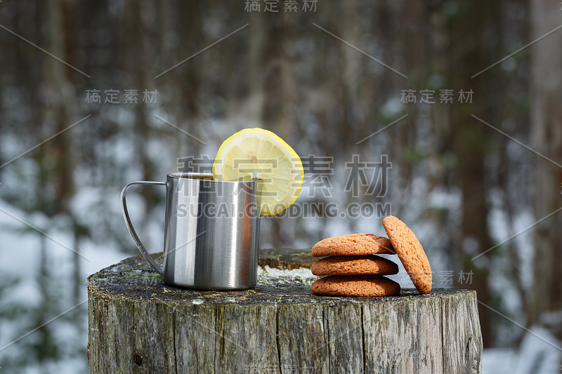 在一个老树桩上放着一个热水瓶，里面放着美味的茶、柠檬和饼干。