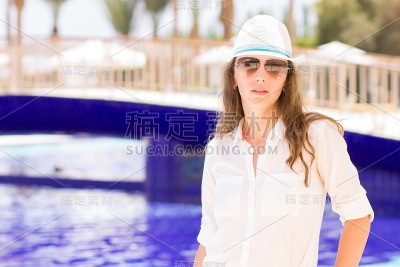 年轻漂亮的女孩站在游泳池旁边