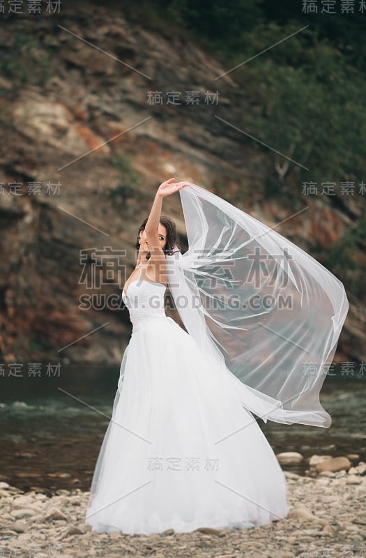 美丽奢华的年轻新娘在长长的白色婚纱和