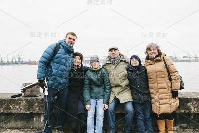 爷爷、父亲、孙子、儿子紧紧地站在一起，拥抱在一起，看着阴沉沉的冬日里的相机