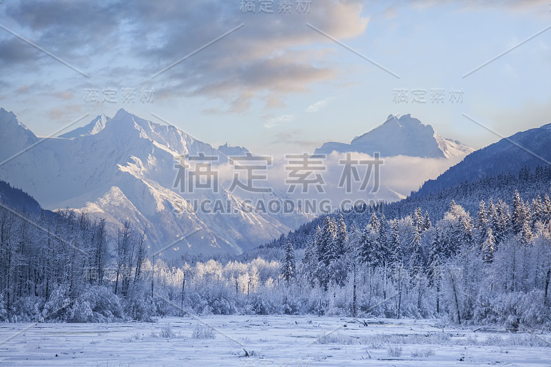 美丽的冬季景色，白雪覆盖的山脉和冰冻的河流与蓝天。