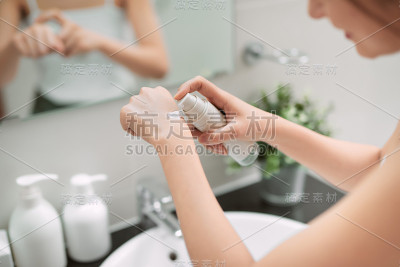 身体保健的概念。沐浴后在手上和指甲上涂抹保湿护手霜的女性。