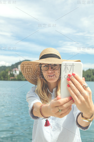 可爱的女孩在湖边用手机。