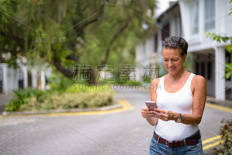 成熟的女游客在新加坡翡翠山路使用手机