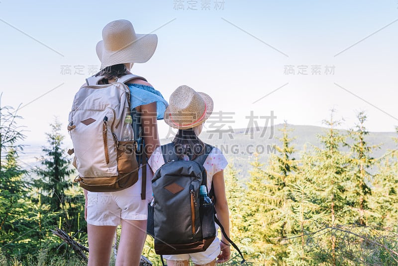 姐妹旅行者背着背包在山间小径欣赏风景