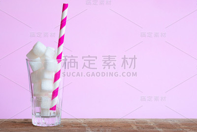 木桌上放着一杯白砂糖。粉色的背景为甜蜜的心情。