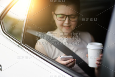 车里的女人用的是智能手机。喝饮料。