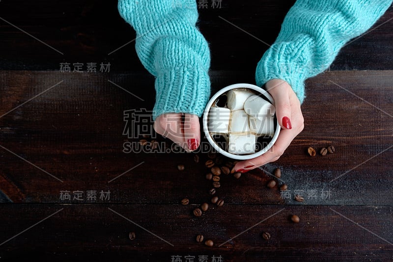 女孩在蓝色毛衣拿着一杯咖啡与棉花糖的手靠近拷贝空间