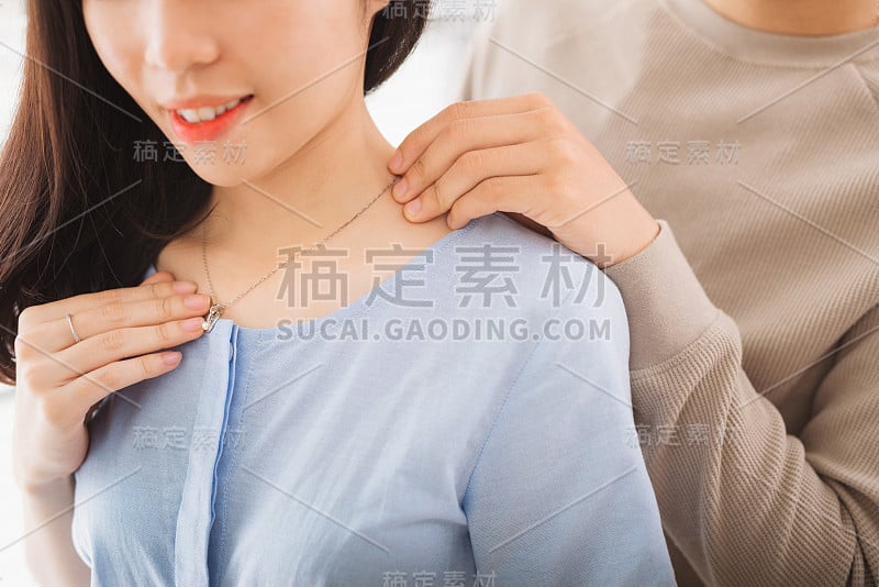 夫妇在爱。男人把项链戴在女孩脖子上。