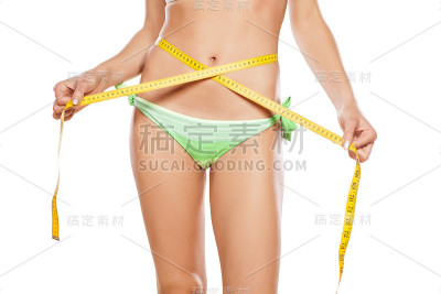漂亮的女孩在量她的腰围