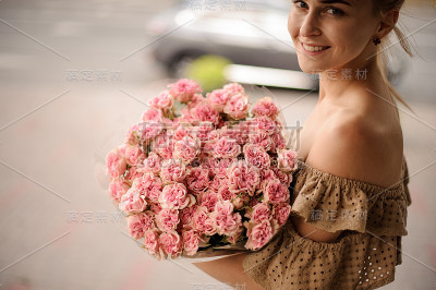 美丽的一束新鲜的小粉红玫瑰在年轻微笑的女人手中
