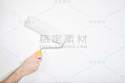 那家伙手里拿着一个滚筒。白色的墙,修复。构建器