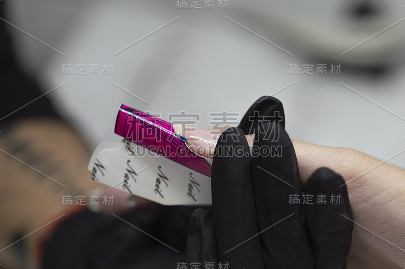 一个女人的手正被美容师涂着凝胶指甲。