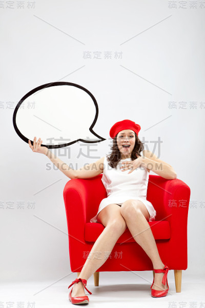 漂亮的女孩坐在红色扶手椅上，还有演讲气球