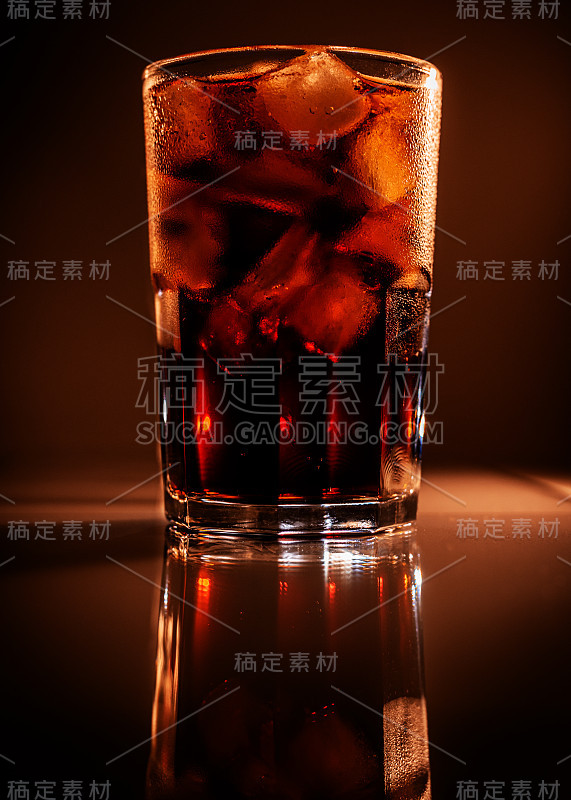 一杯加冰的可乐在棕色的背景上反射。冷饮清爽的碳酸饮料特写。本空间