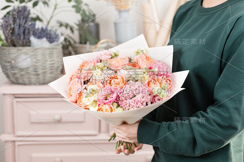 美丽的豪华花束混合鲜花在女人的手里。花店花匠的工作。可爱的可爱的女孩