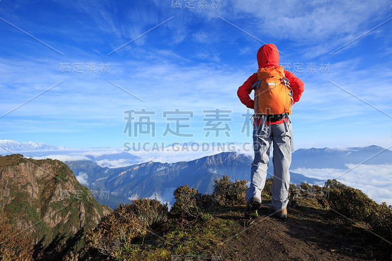 成功的女背包客站在山峰峭壁的边缘