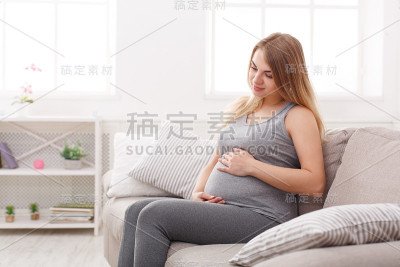 优雅的女人在家里爱抚她的肚子