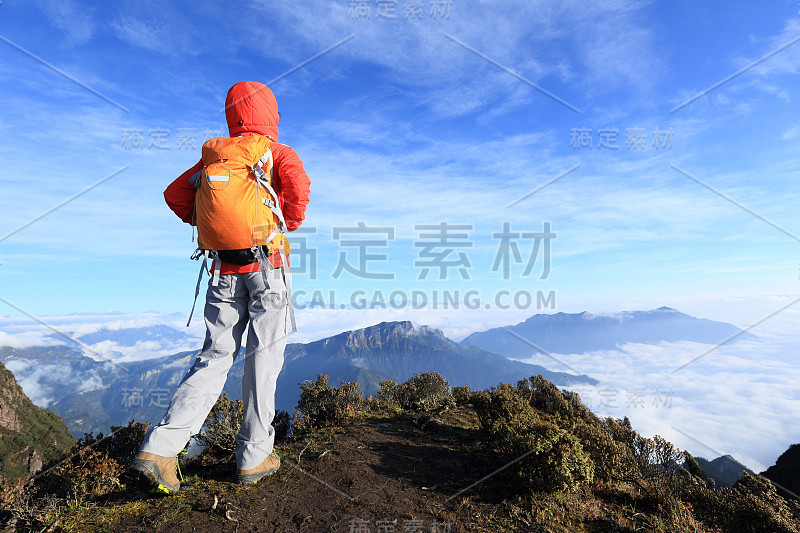 年轻女子在美丽的云峰上徒步