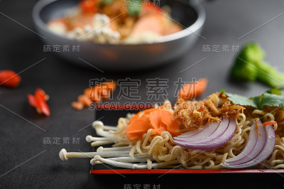 麻辣面条在木托盘上，配料以黑水泥为背景，选择性聚焦