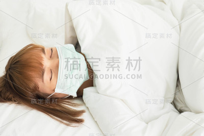 那位妇女因感冒发烧卧床，戴着口罩。