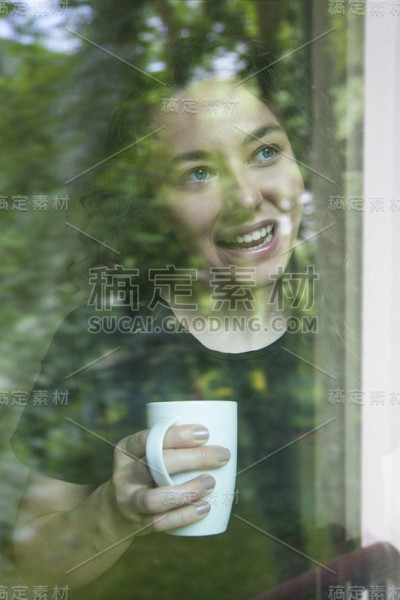年轻女子透过玻璃看窗外