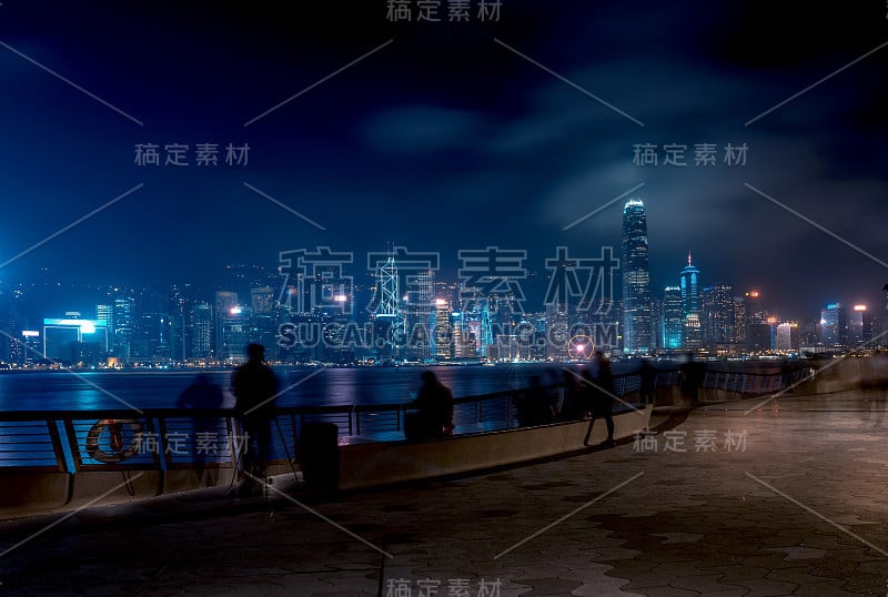 香港城市夜景。在海滨散步的游客