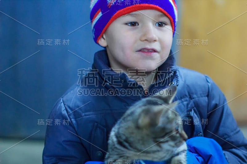 一个穿着冬衣的乡村男孩的肖像，手里拿着一只猫