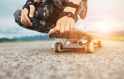 男孩坐在滑板腿和手的特写图像