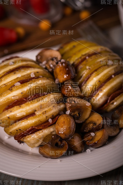 油炸土豆的垂直照片。两个完整的土豆切成片，凹槽里填满奶酪、意大利腊肠和培根。烤蘑菇洒在白色盘子之间。