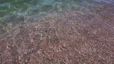透明的水流到沙滩上，沙滩上的浪花