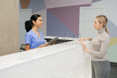年轻女助理站在接待处向病人咨询