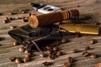 雪茄，打火机和断头台的特写与咖啡豆在粗糙的木头上