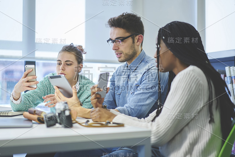 男性和女性最好的朋友在大学图书馆里用数字设备检查wifi连接来做作业，一群自由职业者在小工具上安装应