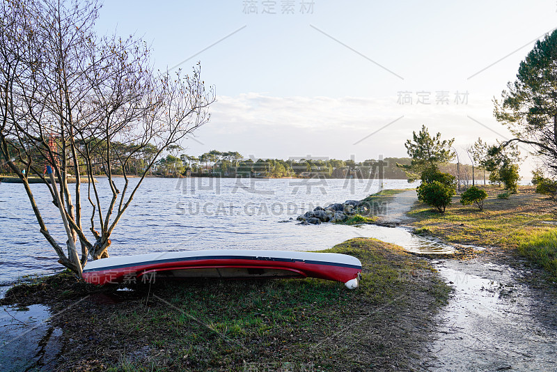 皮划艇和划桨的皮划艇躺在湖边的沙滩上