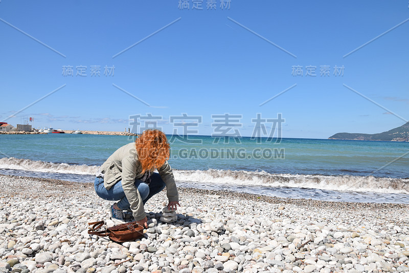 女人在海滩上建造石塔