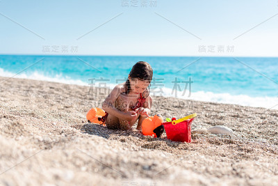可爱的小女孩在美丽的卵石沙滩上玩耍