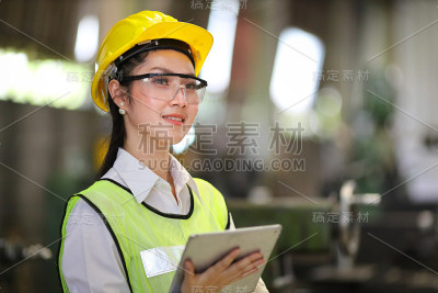 亚洲工程经理戴着安全帽，穿着反光布，正在工厂内用平板电脑检查