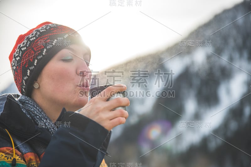 户外荒野探险:一个白人女孩正在喝着一杯金属茶