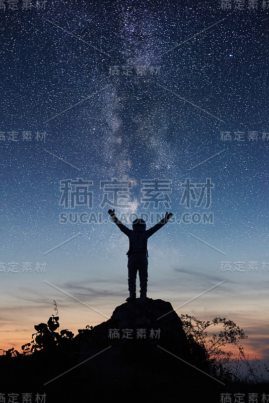 宇航员站在山顶在夜空下。