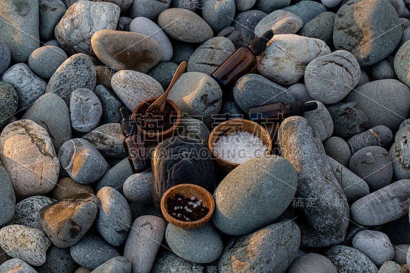 准备自制的咖啡磨砂，用喜马拉雅盐和CBD油在海卵石的背景-库存照片