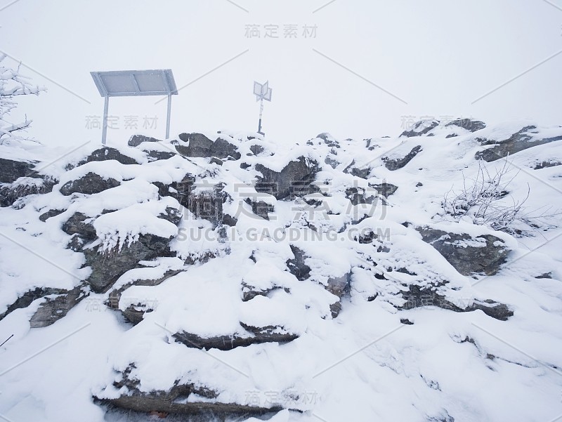 近距离接近岩石地形和新鲜的粉末雪，景观隐藏在浓雾中。