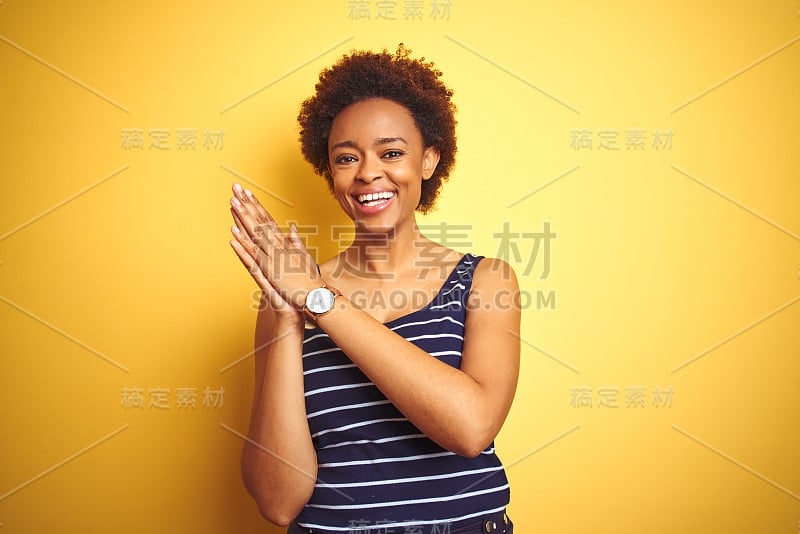 美丽的非裔美国妇女穿着夏天的t恤在孤立的黄色背景鼓掌和高兴的鼓掌，微笑着骄傲的手在一起