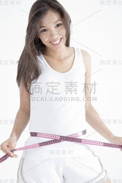年轻女子用卷尺量腰围