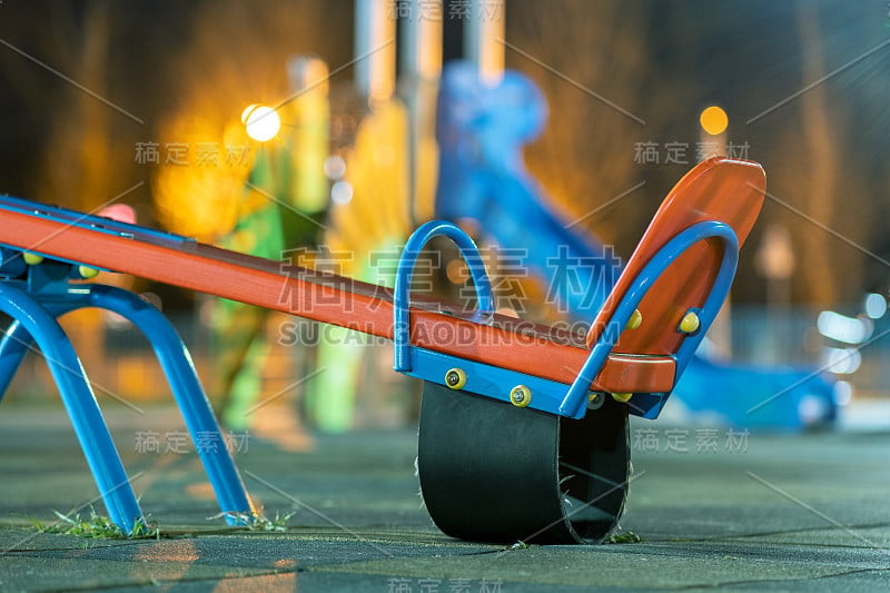 在幼儿园的院子里玩跷跷板，铺着柔软的橡胶地板。